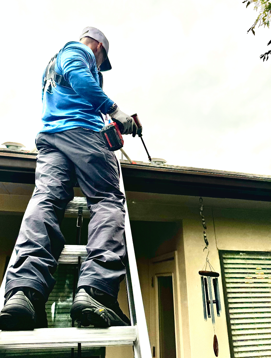Professional on ladder performing gutter service